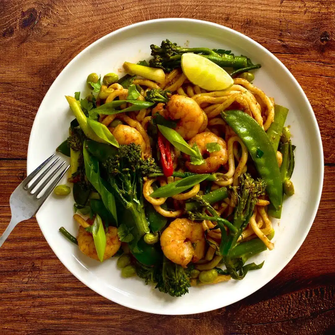 a plate of udon noodles with green vegetables and prawns Prawn Curry Udon